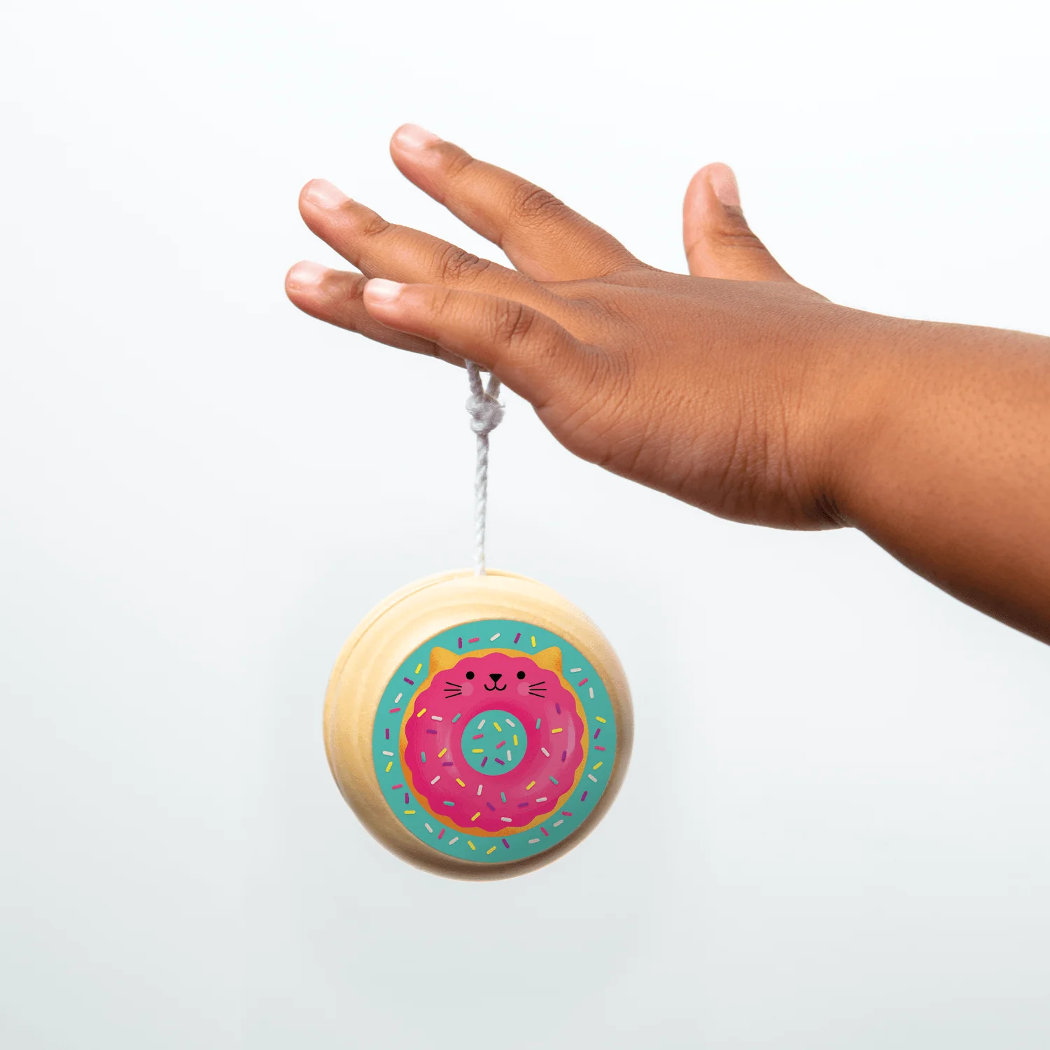 Wooden cat donut yo-yo hanging from a child's finger